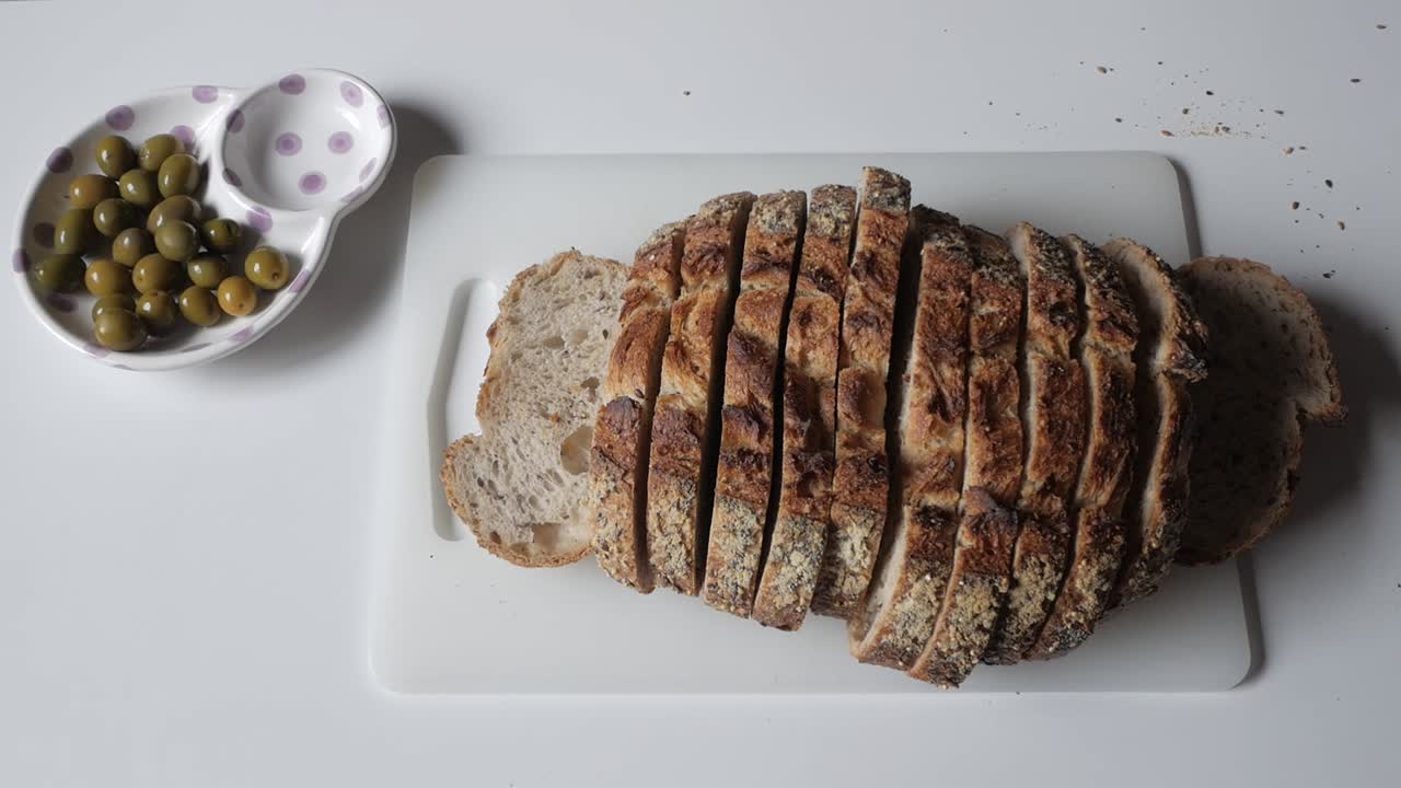 Sliced olive bread with green olives on the side, perfect for a cozy meal or snack