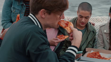 group of friends eating pizza on rooftop enjoying weekend party hanging out together chatting sharing celebration at sunset