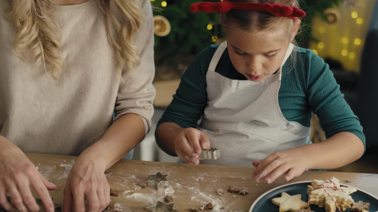 vídeo de seguimiento de una mujer caucásica con su hija haciendo galletas en navidad en la cocina.