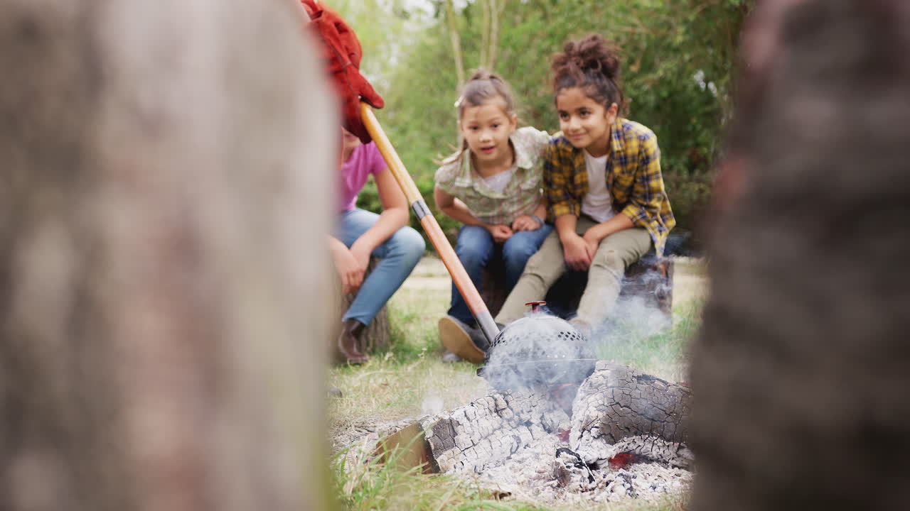 líder de equipo con un grupo de niños en un viaje de actividad al aire libre cocinando comida sobre un fuego de campamento
