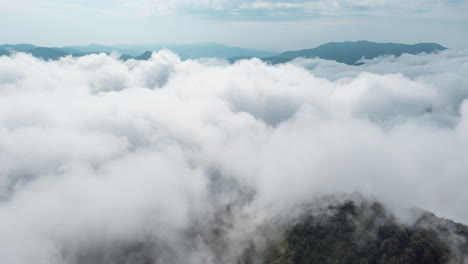 thick clouds blanket the mountain range creating a mystical and serene aerial view