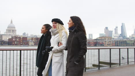 female friends walk along south bank on winter visit to london