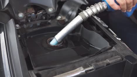 primer plano de la boquilla de combustible de manejo manual que expulsa bencina a la cámara de combustible de motocicletas o scooters