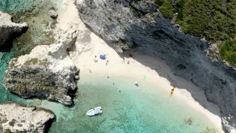 Drohne-Zoomt-Auf-Den-Strand-Der-Insel-Tremiti,-Wo-Menschen-Schwimmen-Und-Am-Ufer-Spazieren-Gehen