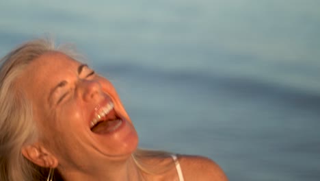 Primer-Plano-De-Una-Mujer-Rubia-Madura-Mirando-A-La-Cámara-Jugando-Con-Gafas-De-Abuela-Y-Riendo