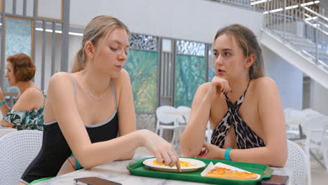 Two teenage girls eating lunch and talking