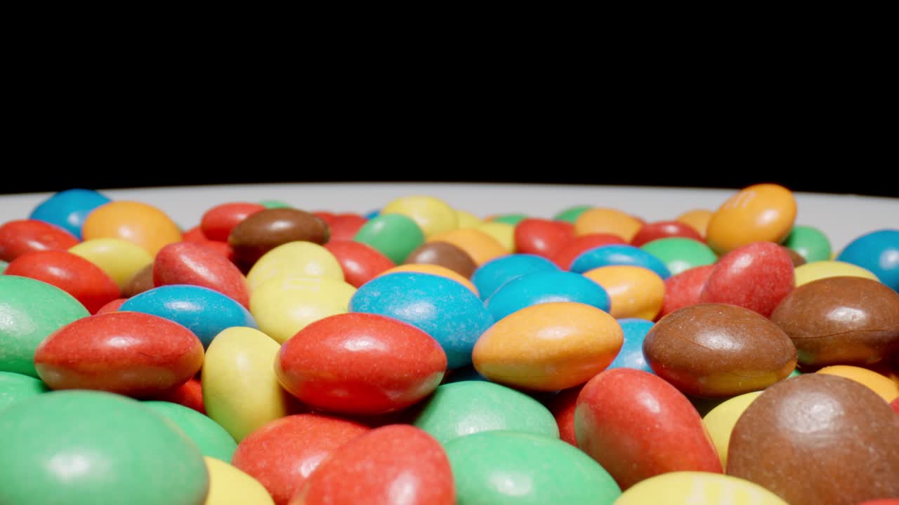 macro: movimiento sobre caramelos de color sobre un fondo negro