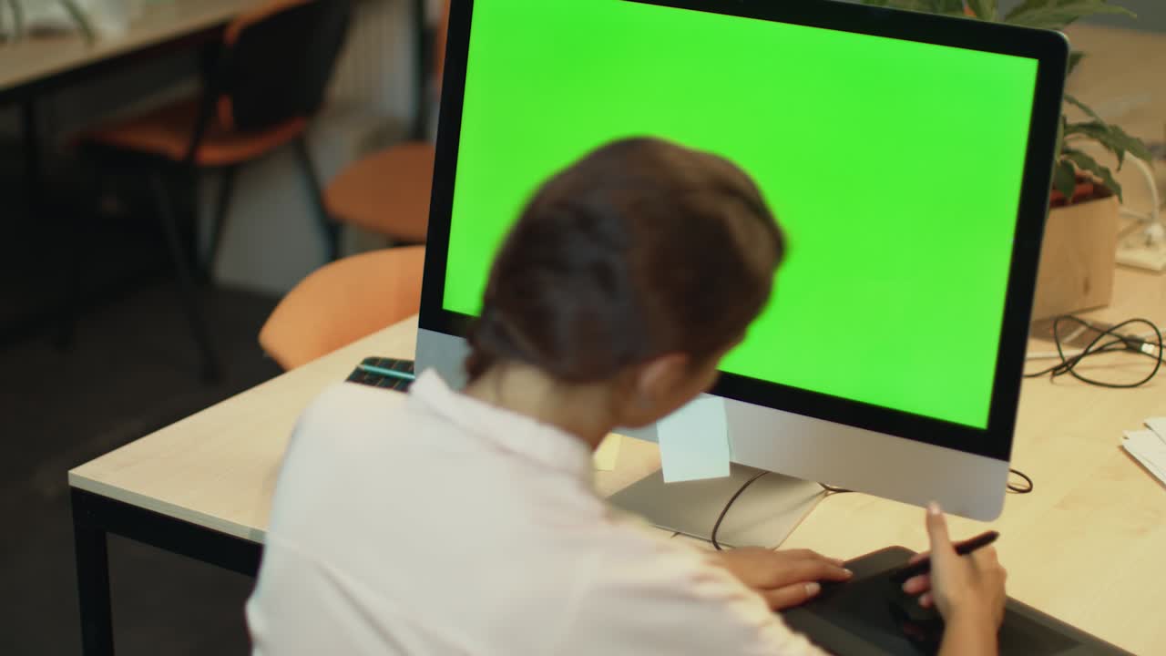 mujer joven trabajando en una computadora con pantalla verde en la oficina. diseñador gráfico