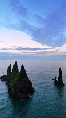 sharp rocks stick out from the waterscape. sea-gulls fly around the rocks. top view on the atlantic ocean at the shore of iceland. vertical video.