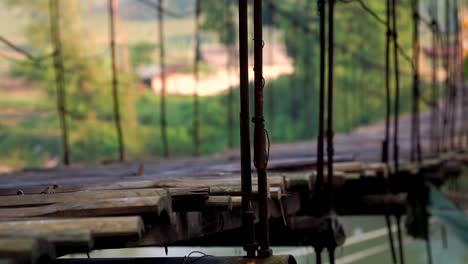 Wooden-suspension-bridge-with-metal-sling-rope-is-swaying-because-passed-by-motorcycle