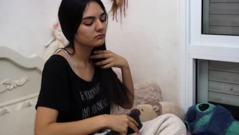 girl sitting on the bed brushing her hair