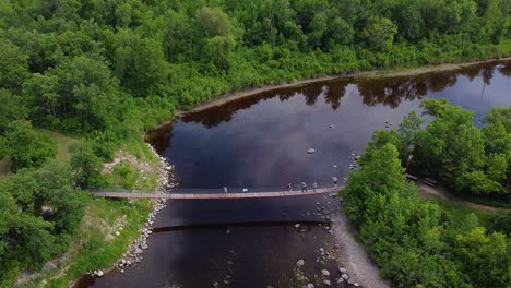 flying over swinging bridge deep in forest river tourists