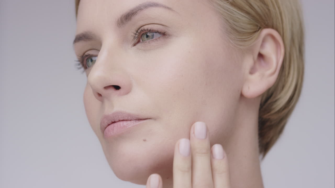 hermosa mujer sana tocando la piel lisa en la cara en cámara lenta para el concepto de cuidado de la piel de belleza en un fondo gris dragón épico rojo