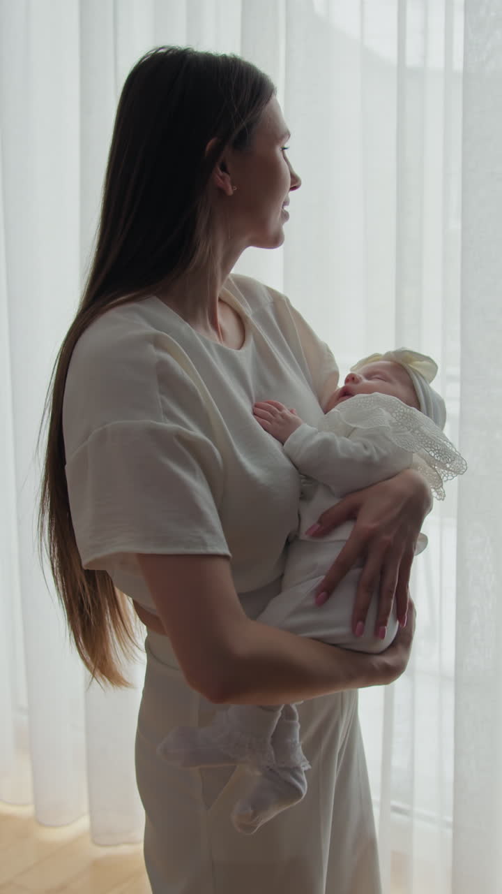 Madre tierna acuna a su hija bebé que duerme plácidamente, bañada en suave luz natural cerca de un