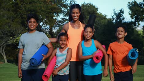 Portrait-of-instructor-standing-with-exercise-mat