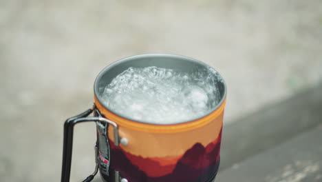 close up shot of a man picking spoon from a boiling water in an enamel red and yellow tourist mug