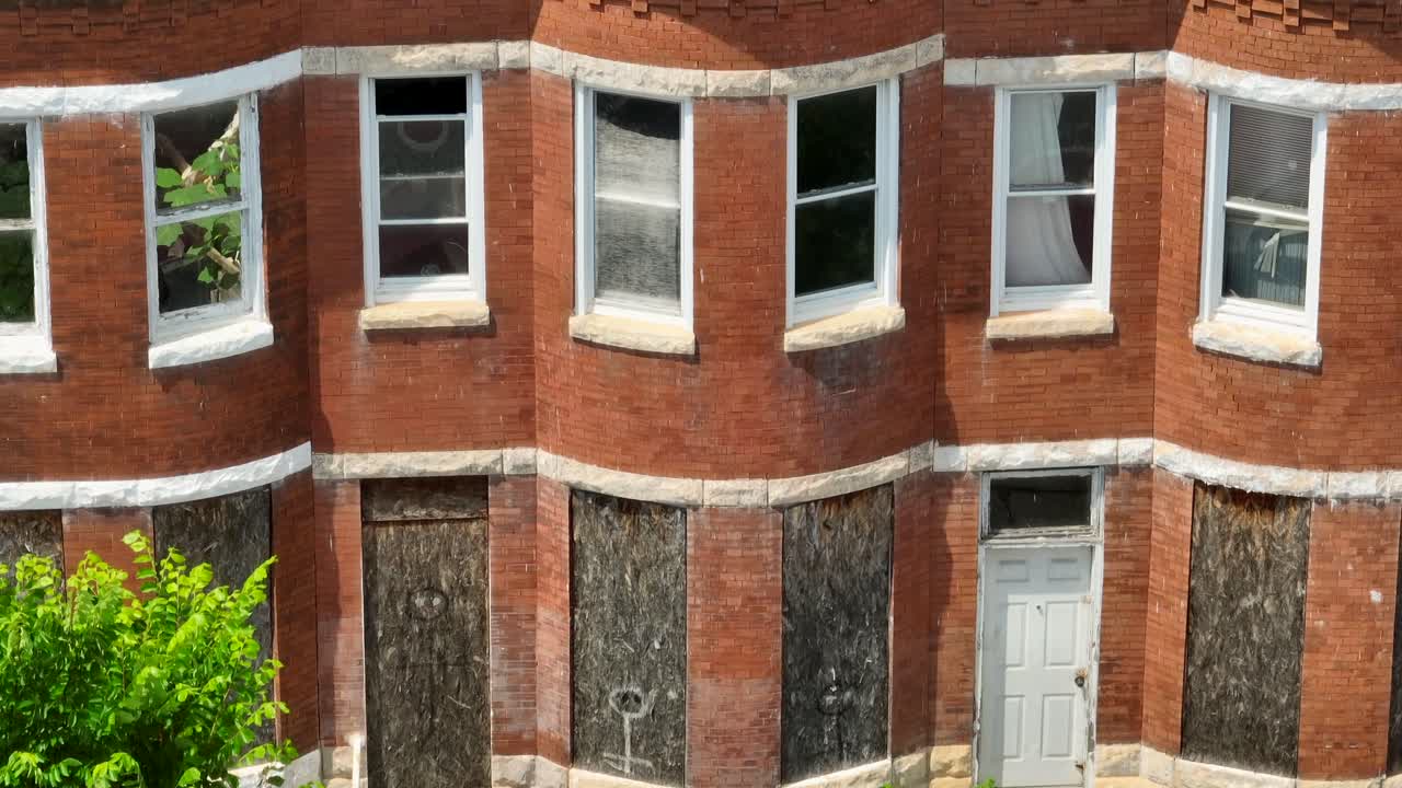 Abandoned boarded up rowhomes in USA. American poverty in inner city urban setting. Aerial tilt up reveal