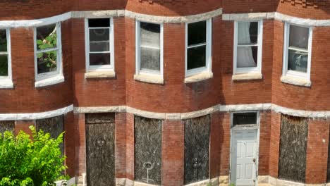 abandoned boarded up rowhomes in usa. american poverty in inner city urban setting. aerial tilt up reveal