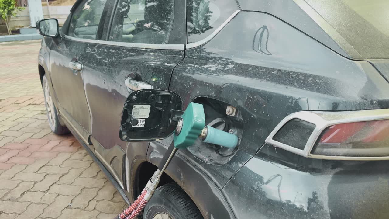 tilt up shot showing cng gass being filled to a car, a car being refueled with CNG at a gas station