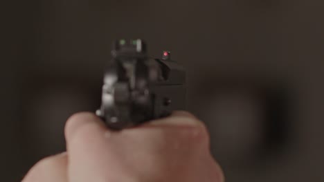 overshoulder of pistol being aimed at an obscure subject in a dark building