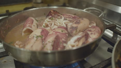 seafood in a cooking pan while the sauce is simmering on a gas flame stove