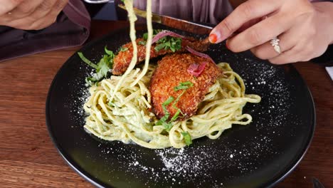 closeup of a woman eating chicken and pasta