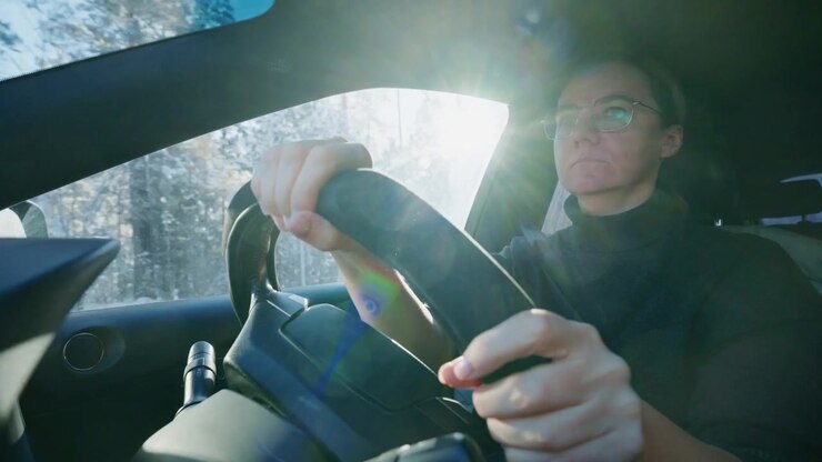 Donna che guida un'auto attraverso un paesaggio forestale innevato