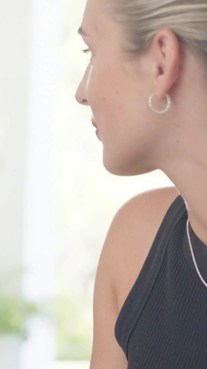Video verticale: Donna con top nero che si gira vicino alla finestra, telecamera fissa, mostrando il profilo, spazio per il testo
