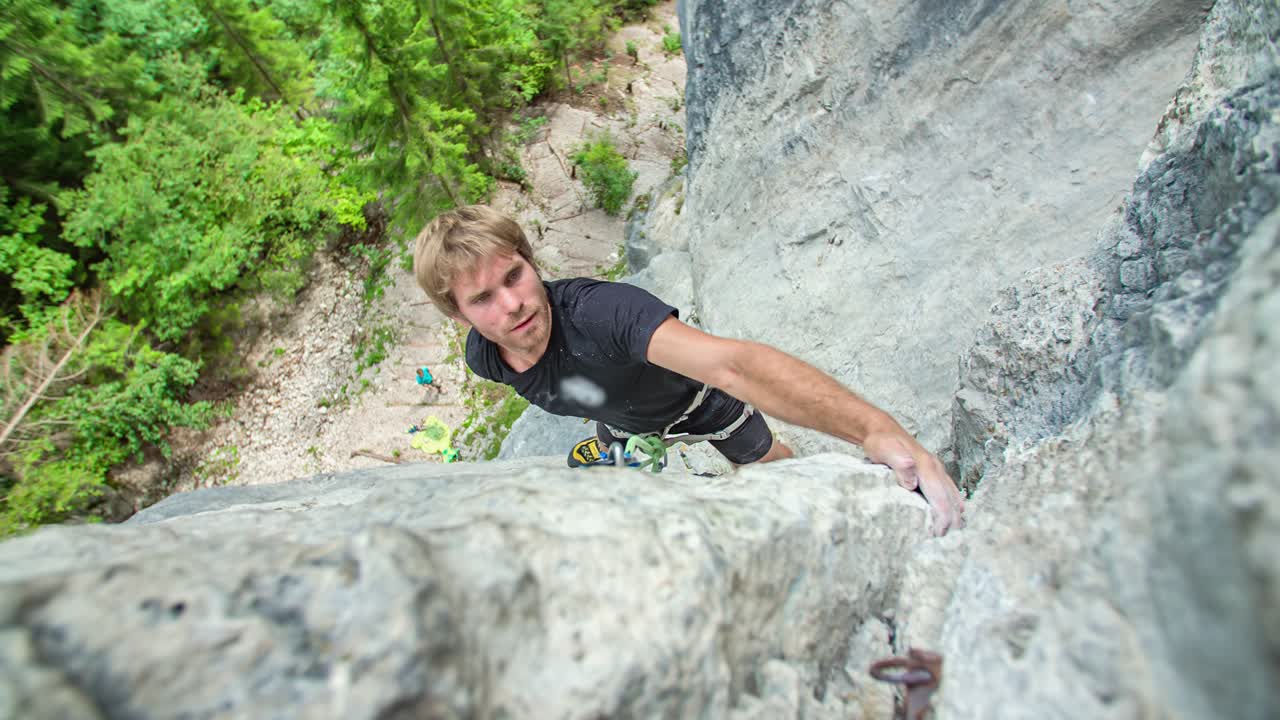 Man rock climbing the face of a Burjakove peci cliff, with rope and hook