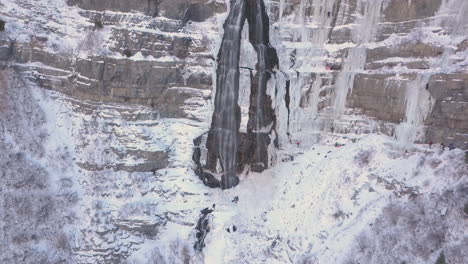 ice climbers work up the side of a frozen waterfall - zooming out