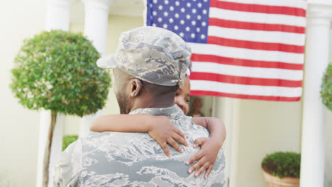 african american male soldier embracing his smiling daughter over american flag