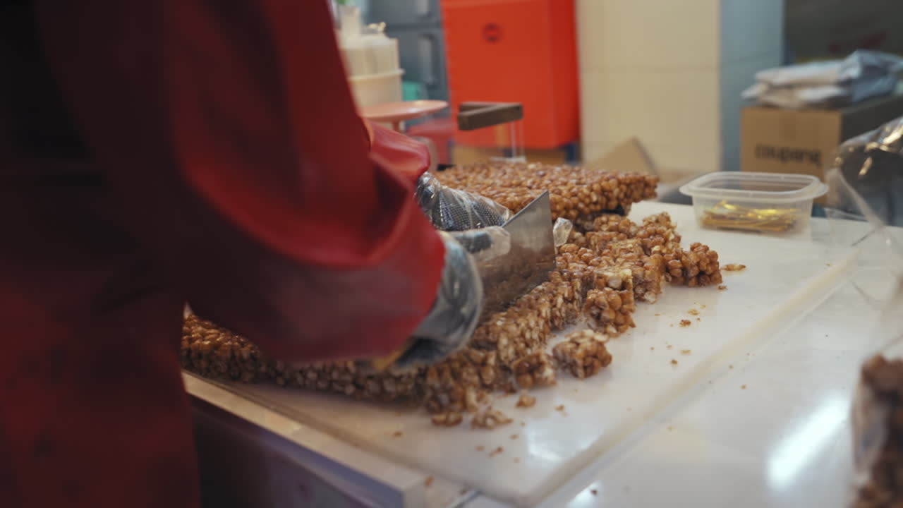 Vendor cutting Korean traditional sweet rice puff snack in bulk at Gwangjang Market in Seoul Korea, medium dolly in slow motion