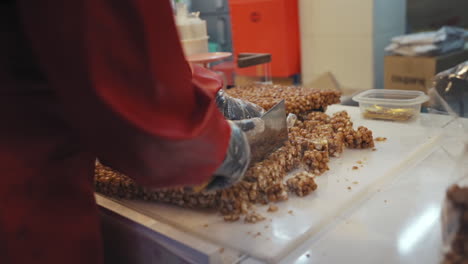 Vendor-cutting-Korean-traditional-sweet-rice-puff-snack-in-bulk-at-Gwangjang-Market-in-Seoul-Korea,-medium-dolly-in-slow-motion