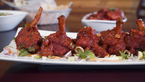 chicken lollipops lined up on white plate, fried wings marinated in chili, slider close up 4k