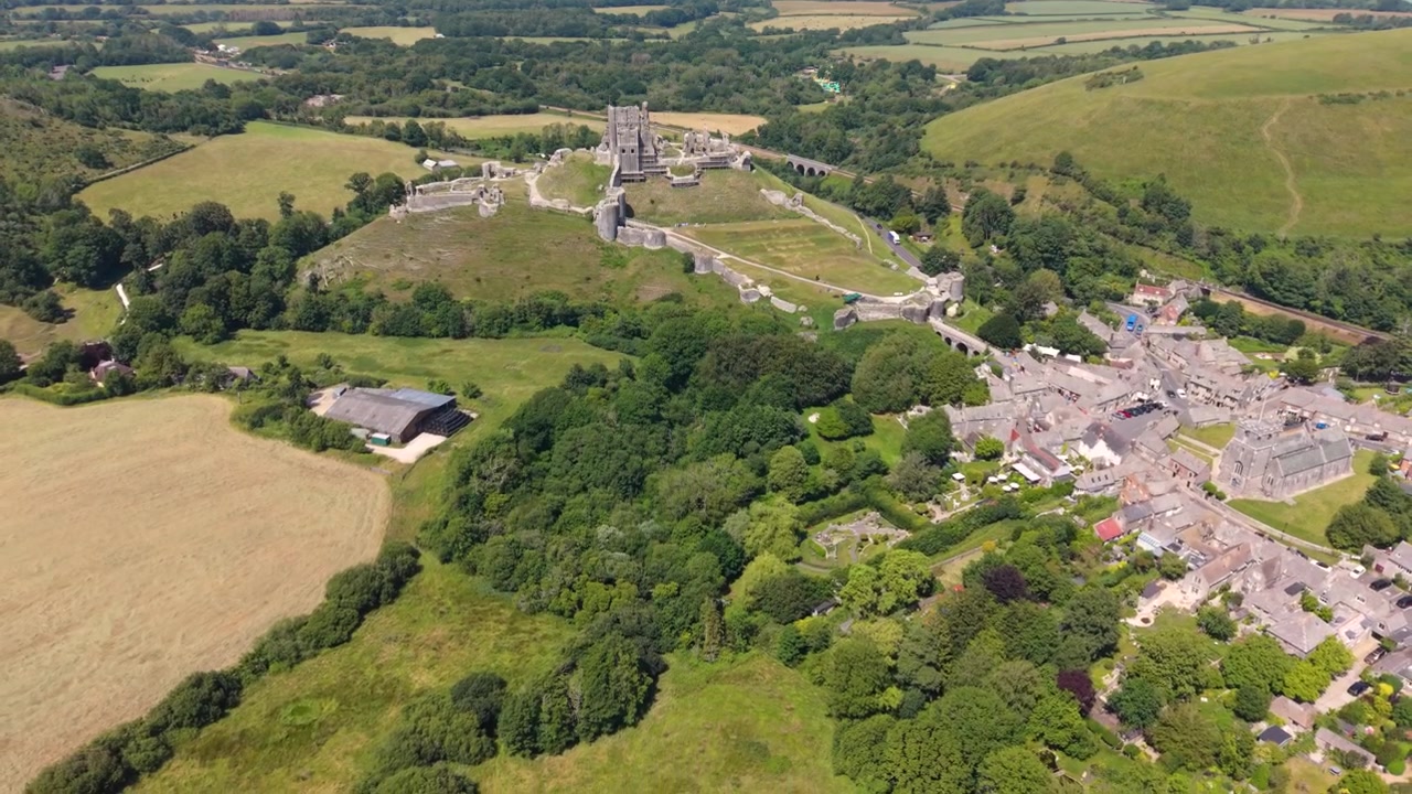 Corfe Castle Isle of Purbeck Dorset, England, high,slow,backwards drone footage of castle and village looking down on the ruins with views of the rolling surrounding countryside on bright sunny day