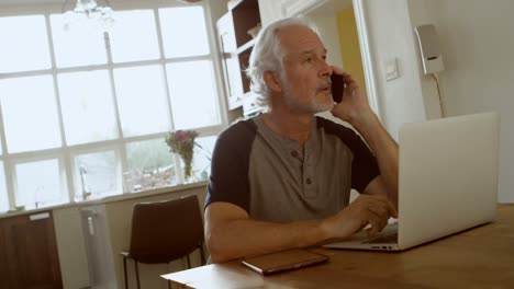 senior man talking on mobile phone sitting at the table 4k