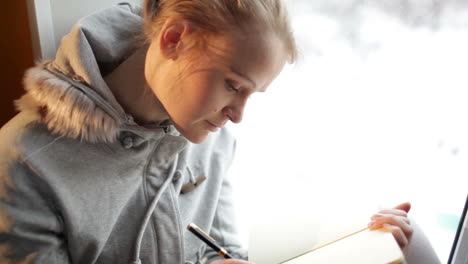 young beautiful girl writing in her journal and daydreaming