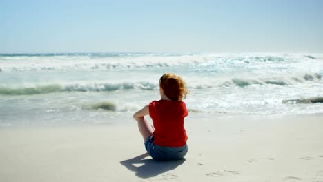 mujer sentada en la arena y mirando al mar 4k