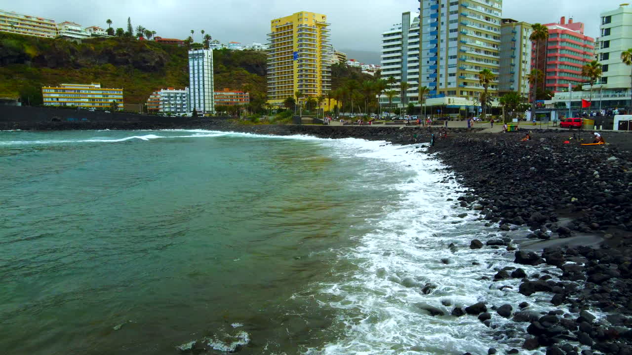video aéreo de las olas chocando contra la playa de roca negra
