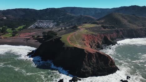 drone footage of beach and waves hitting rock cliffs