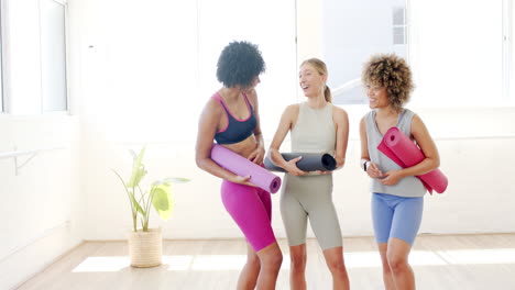 Tres-Mujeres-Están-Paradas-En-Un-Brillante-Estudio-De-Yoga,-Sosteniendo-Colchonetas