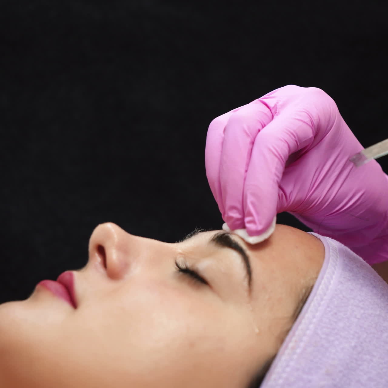 Female cosmetologist using ultrasonic scrubber on client's face. Professional ultrasonic equipment.