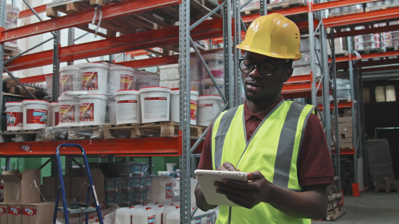 Busy Black Male Warehouse Worker with Tablet
