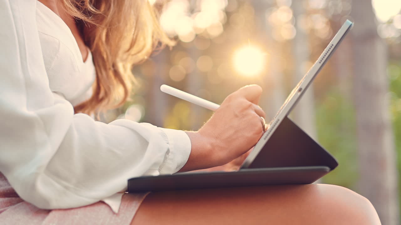 Woman sketching on a tablet with a stylus pen in the park