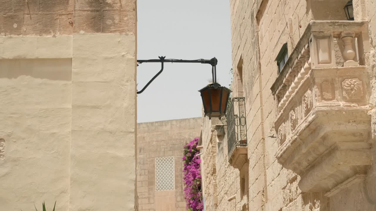 Lampada su un muro di un edificio lungo una strada medievale in una giornata di sole