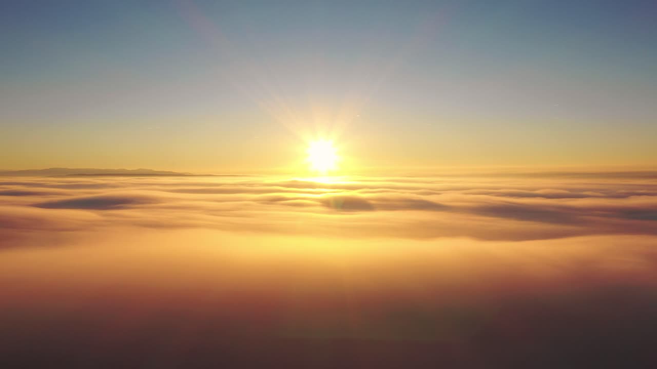 Drone aerial flight to sun at sunrise above clouds, panning heavenly sky panorama