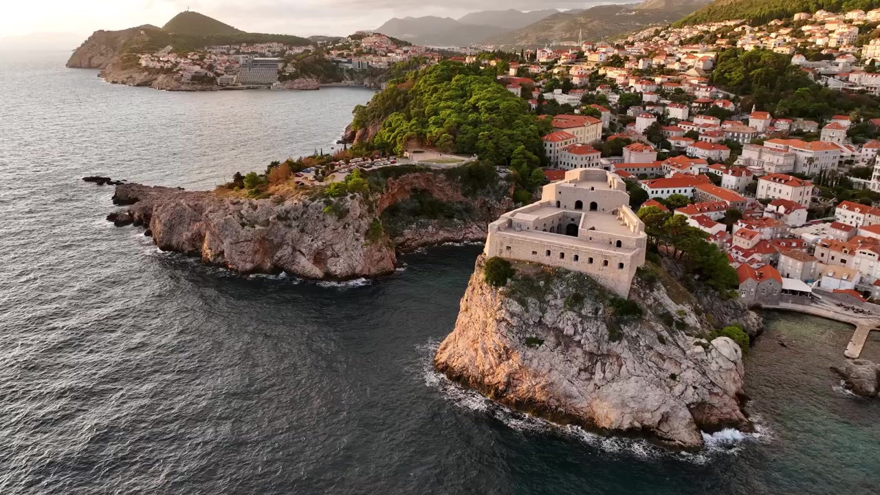 Drone in orbita su un edificio torre di guardia sulla costa di Dubrovnik, con le mura storiche della Città Vecchia che si affacciano sul Mare Adriatico.