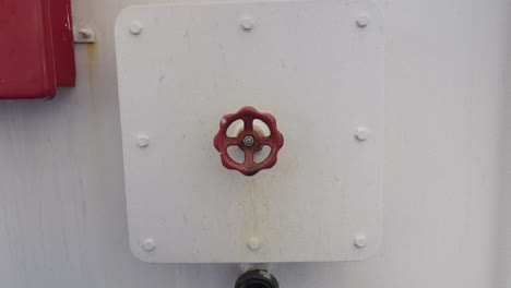 round red metal valve for water pipe on white wall onboard of a vessel