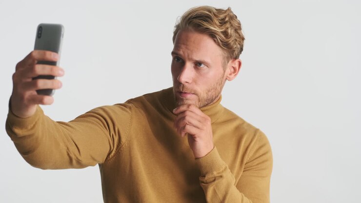 Uomo attraente in maglione che si scatta un selfie.