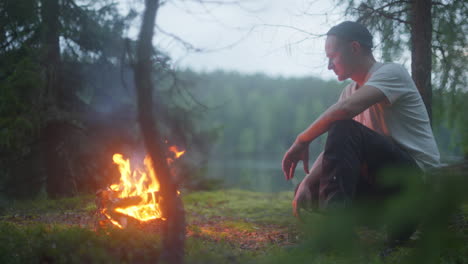 man sitting infront of fire in the woods